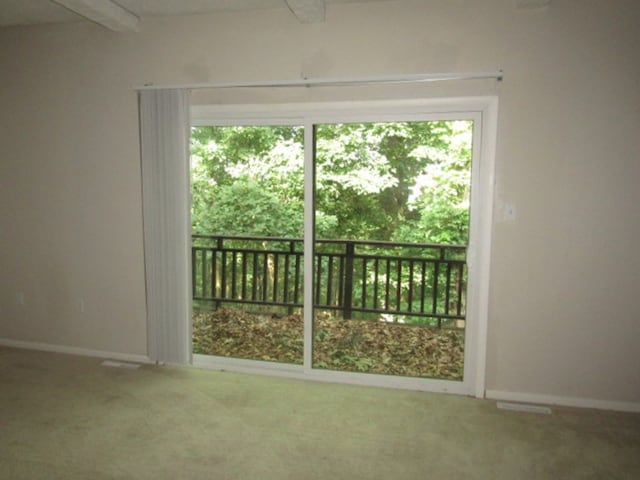 carpeted spare room with beamed ceiling