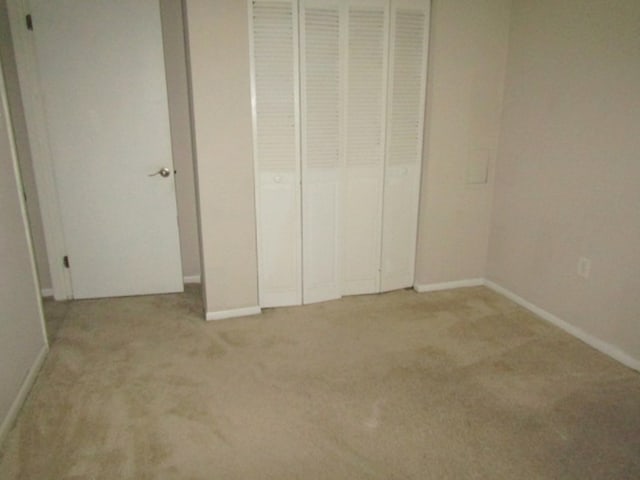 unfurnished bedroom featuring light colored carpet and a closet