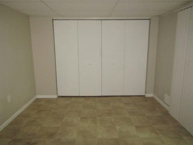 unfurnished bedroom with a paneled ceiling and a closet