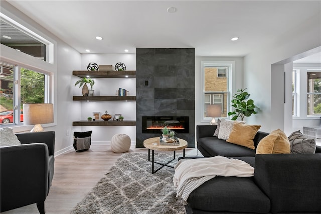 living room with light wood-type flooring and a tile fireplace