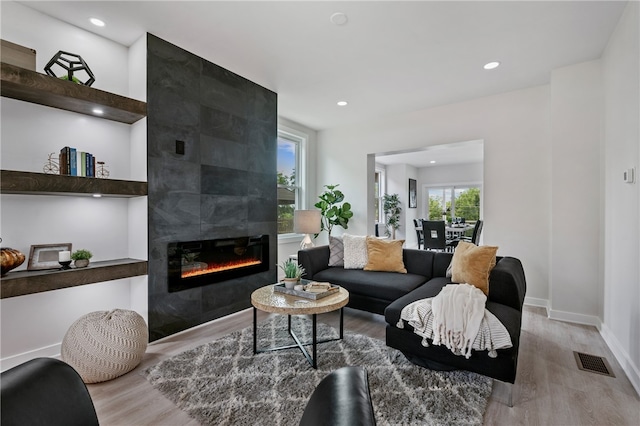 living room with a tiled fireplace and light hardwood / wood-style floors