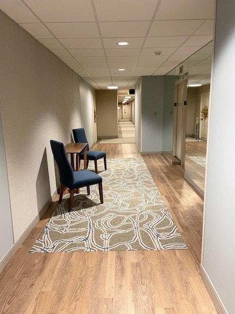 living area with light wood-type flooring and a drop ceiling