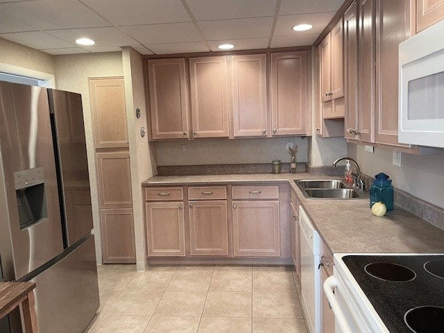 kitchen featuring a paneled ceiling, white appliances, light tile patterned floors, and sink