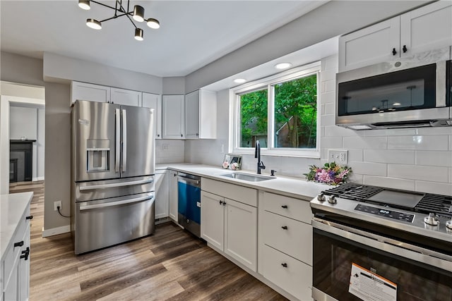 kitchen with white cabinetry, a chandelier, sink, dark hardwood / wood-style floors, and appliances with stainless steel finishes