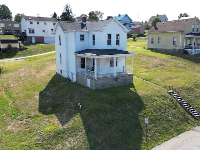 back of property with a yard and covered porch