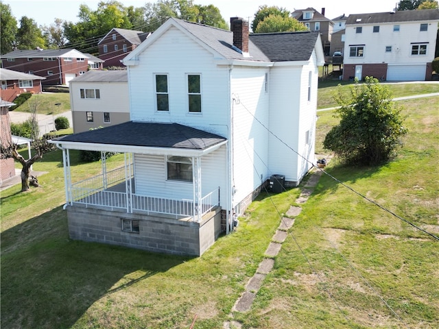 back of property featuring a yard, a garage, and covered porch