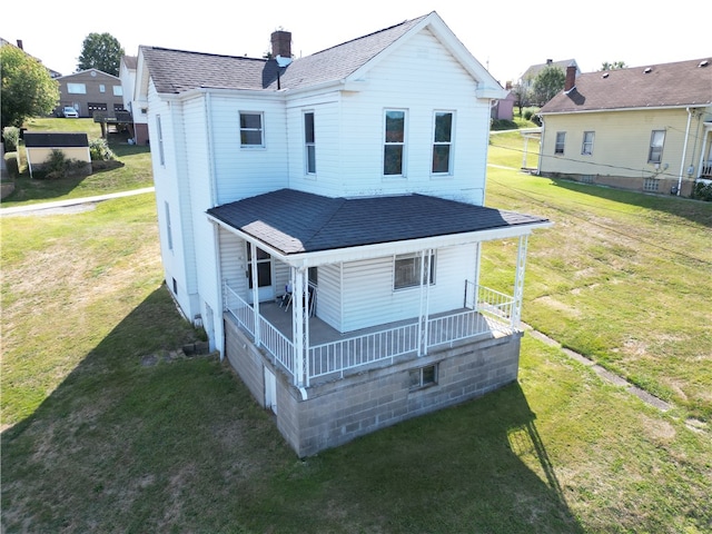 back of property featuring a lawn and covered porch