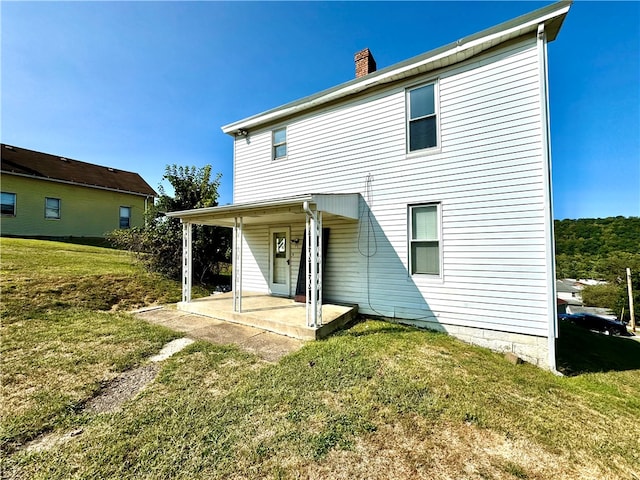 rear view of house featuring a lawn and a patio area