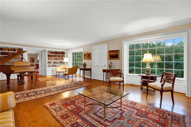 living room featuring hardwood / wood-style floors, built in shelves, and crown molding