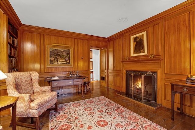 sitting room featuring dark wood-type flooring, wood walls, and ornamental molding