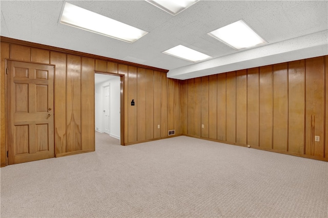 basement with wood walls and light colored carpet