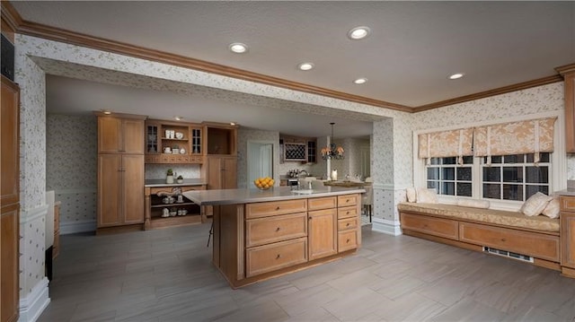 kitchen with a kitchen bar, a center island, decorative light fixtures, and crown molding