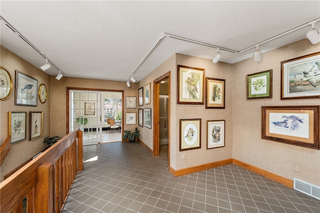 hall with track lighting and dark tile patterned flooring