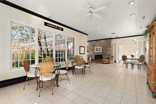 tiled dining area with ceiling fan, ornamental molding, wooden ceiling, and a fireplace