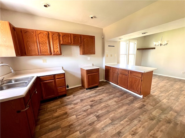 kitchen featuring hanging light fixtures, a chandelier, sink, kitchen peninsula, and dark wood-type flooring