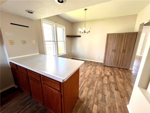 kitchen with pendant lighting, a notable chandelier, a textured ceiling, kitchen peninsula, and dark wood-type flooring