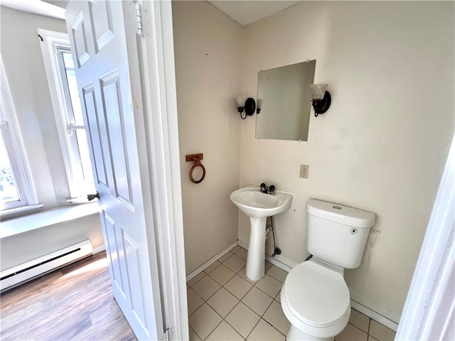 bathroom featuring a baseboard heating unit, toilet, sink, and tile patterned floors