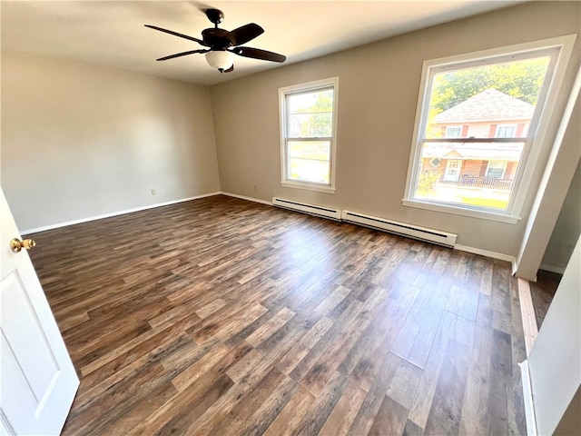 unfurnished room featuring a wealth of natural light, dark wood-type flooring, ceiling fan, and a baseboard heating unit