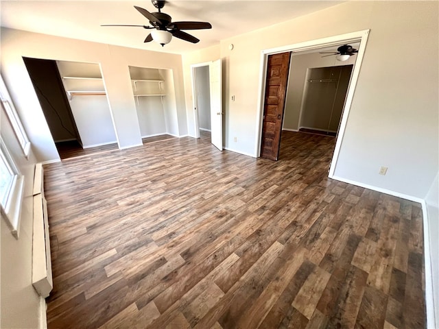 unfurnished bedroom featuring two closets, ceiling fan, and dark hardwood / wood-style floors