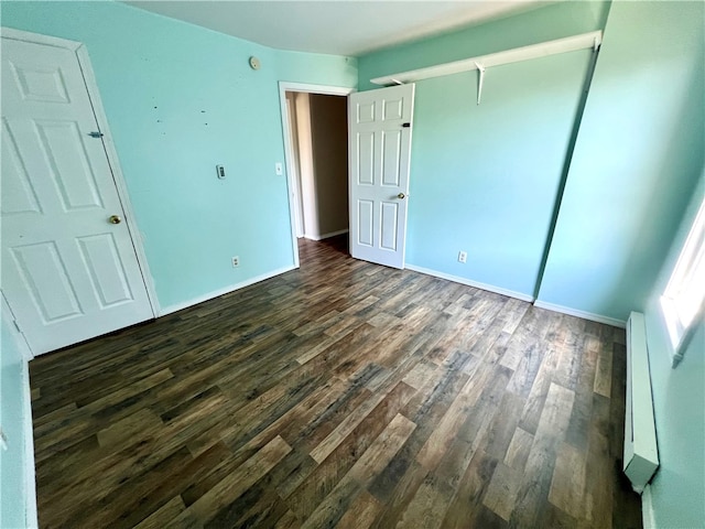 unfurnished bedroom with a baseboard radiator and dark hardwood / wood-style flooring