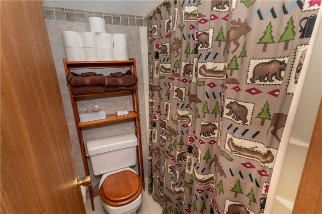 bathroom with tile patterned floors, toilet, and tile walls