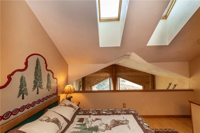 bedroom featuring hardwood / wood-style floors and vaulted ceiling with skylight