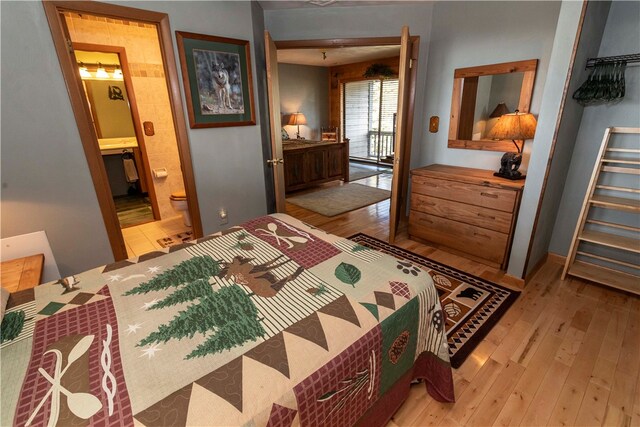 bedroom featuring connected bathroom and light hardwood / wood-style flooring