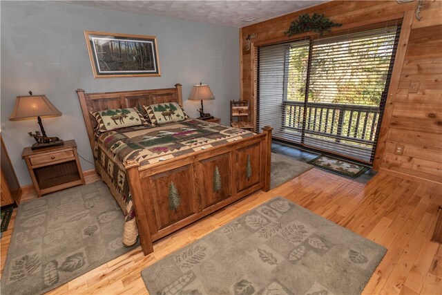 bedroom featuring a textured ceiling, light wood-type flooring, and wooden walls