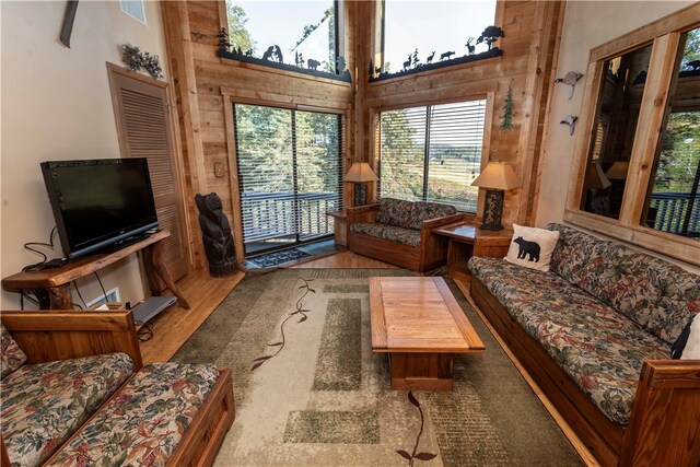 living room with hardwood / wood-style floors, a towering ceiling, and wooden walls