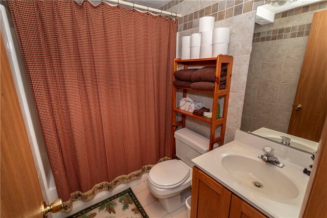 bathroom featuring tile patterned flooring, vanity, toilet, and tile walls