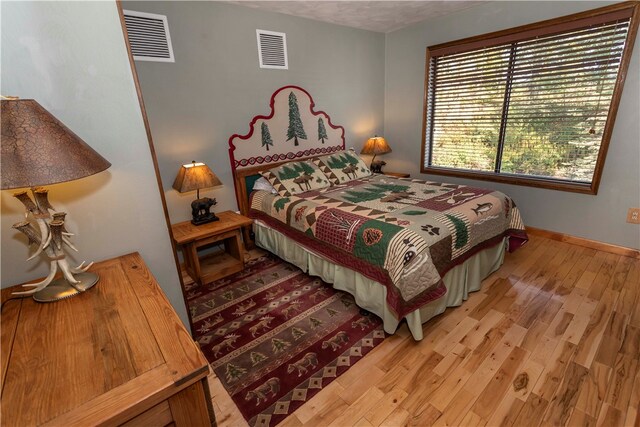 bedroom with a textured ceiling and light hardwood / wood-style flooring