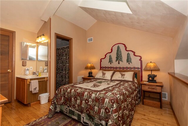 bedroom featuring light hardwood / wood-style flooring, lofted ceiling, and sink