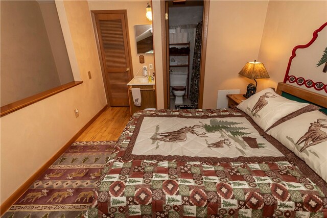 bedroom featuring hardwood / wood-style flooring, connected bathroom, and a closet