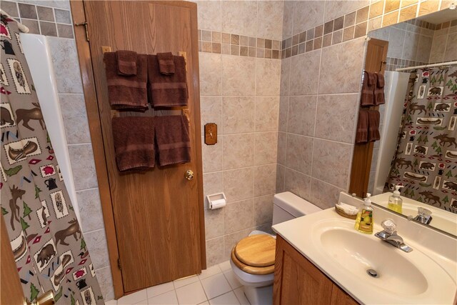 bathroom with tile patterned flooring, vanity, toilet, and tile walls