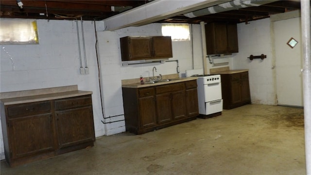 kitchen featuring white range, sink, and dark brown cabinetry