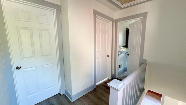 corridor featuring dark wood-style floors, an upstairs landing, and baseboards