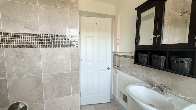 bathroom with visible vents, backsplash, tile patterned floors, tile walls, and a sink