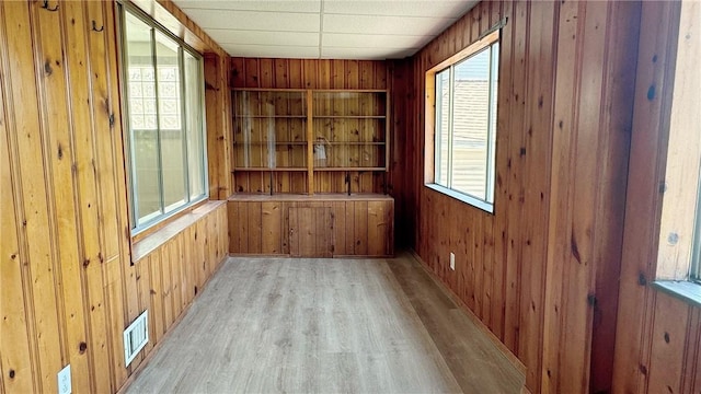 interior space featuring visible vents, wood walls, and light wood finished floors