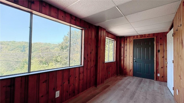 unfurnished sunroom featuring a drop ceiling and a wealth of natural light