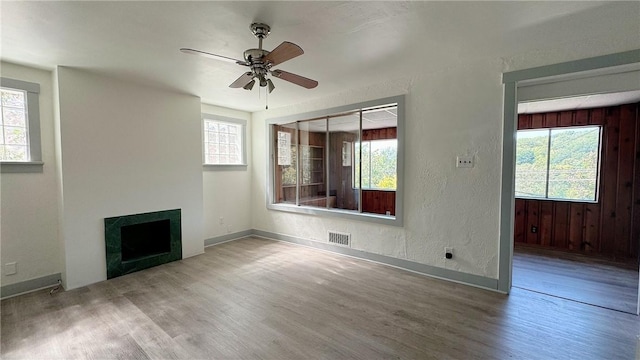 unfurnished living room with visible vents, a healthy amount of sunlight, wood finished floors, and a fireplace