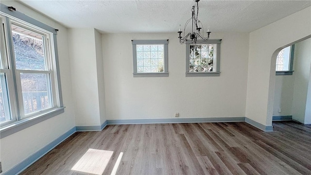 unfurnished dining area with a chandelier, baseboards, and wood finished floors