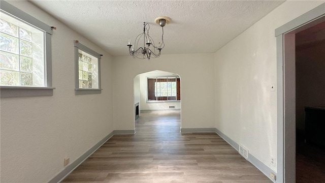 858 Monteiro St, Greenfield, PA 15217 - hallway with arched walkways, a textured ceiling, wood finished floors, a chandelier, and baseboards