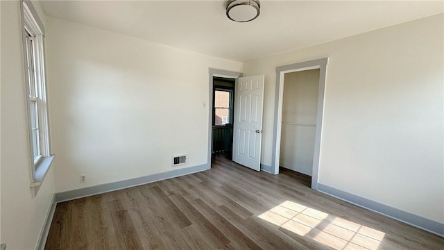 unfurnished bedroom with visible vents, baseboards, and wood finished floors