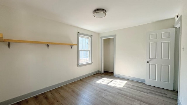 unfurnished bedroom with a closet, baseboards, and wood finished floors