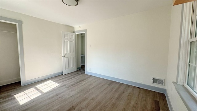 unfurnished bedroom featuring visible vents, baseboards, and wood finished floors