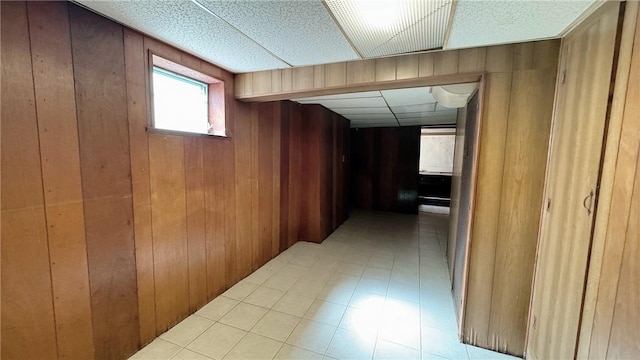 hall with wooden walls and a drop ceiling