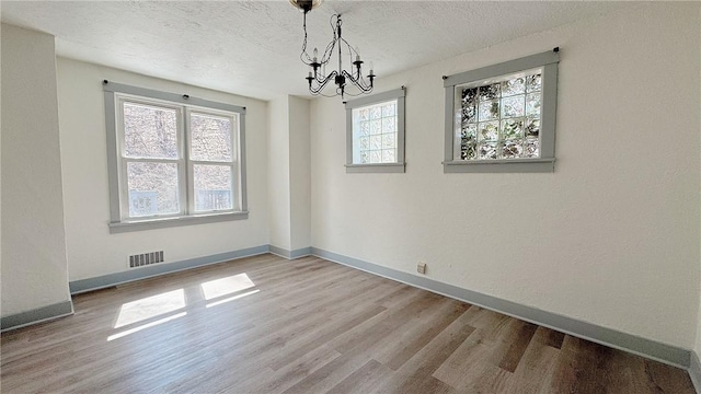858 Monteiro St, Greenfield, PA 15217 - unfurnished dining area featuring a chandelier, wood finished floors, a textured ceiling, and baseboards