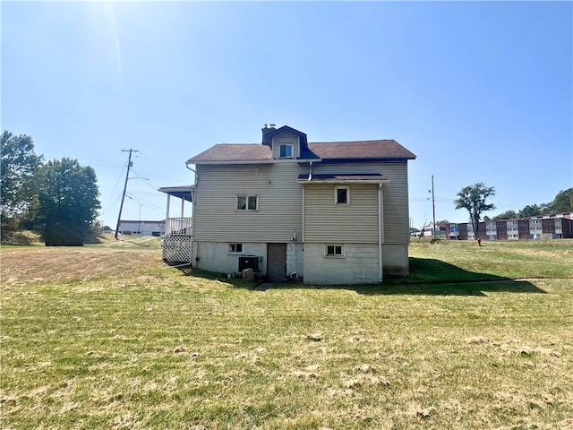 rear view of house featuring cooling unit and a yard