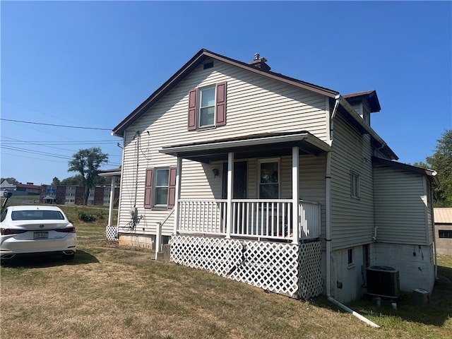 view of front facade featuring cooling unit, a front lawn, and covered porch