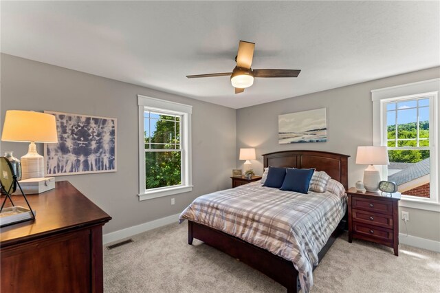 bedroom featuring multiple windows, ceiling fan, and light carpet